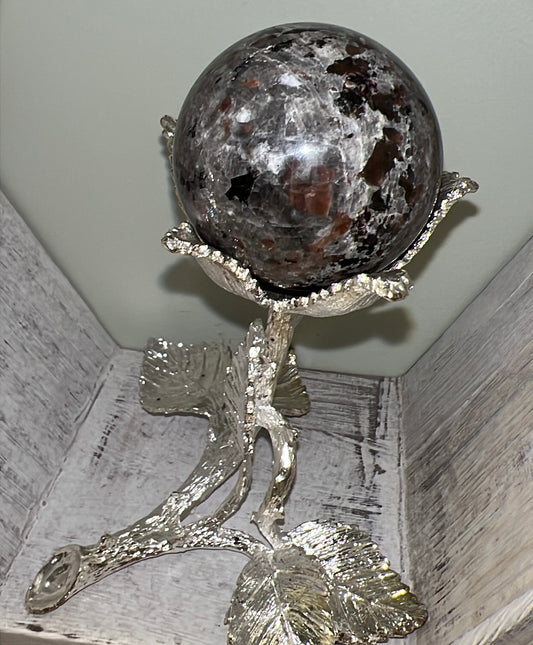 Gray and brown sphere held in silver floral stand.