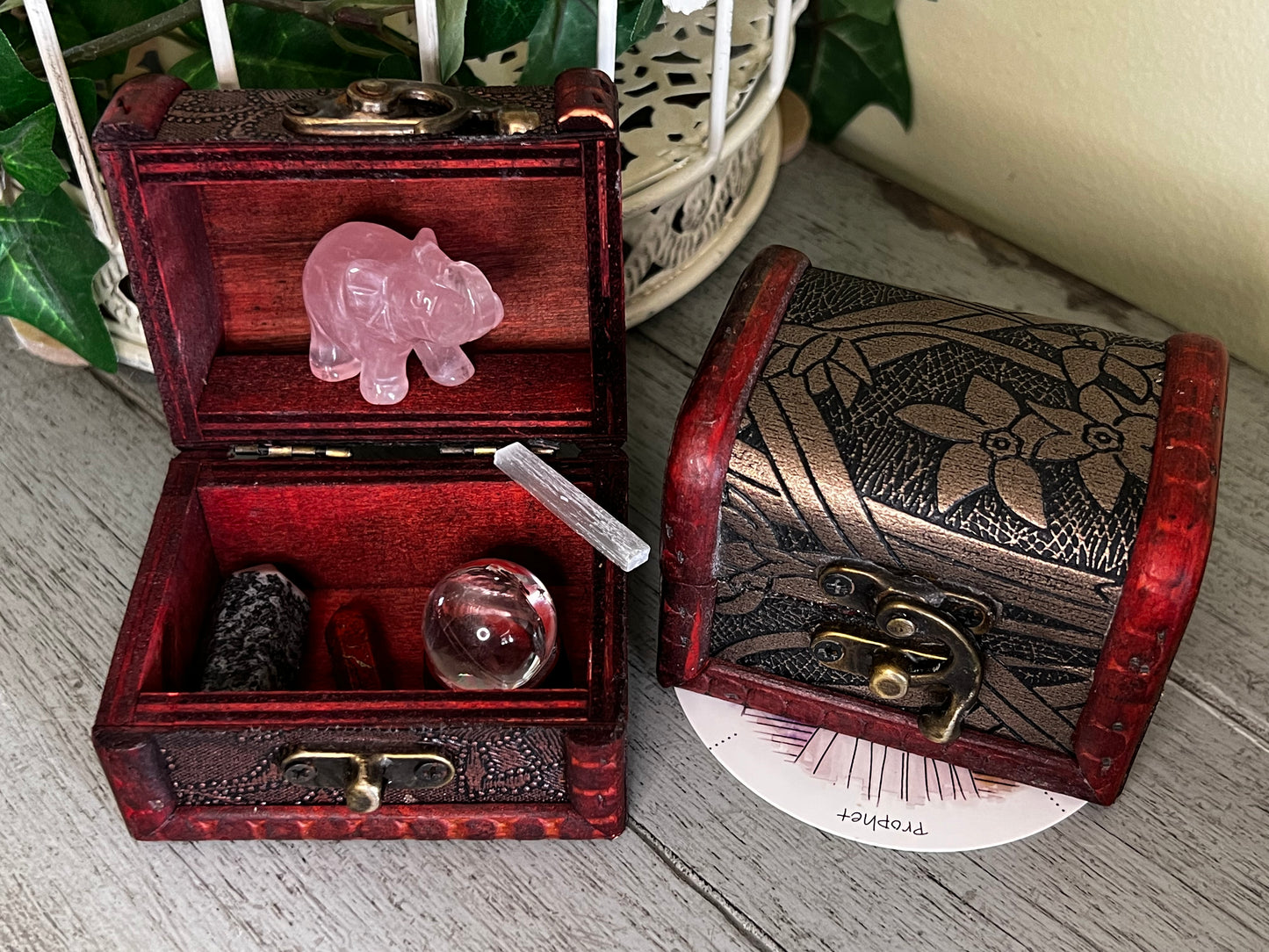 Two open wooden treasure chests with crystals, including a rose quartz elephant.
