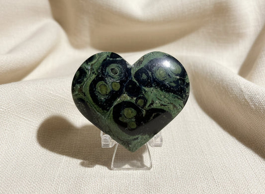 beautiful close-up of a carved heart material is kambaba jasper light greens dark greens, and black swirls throughout
