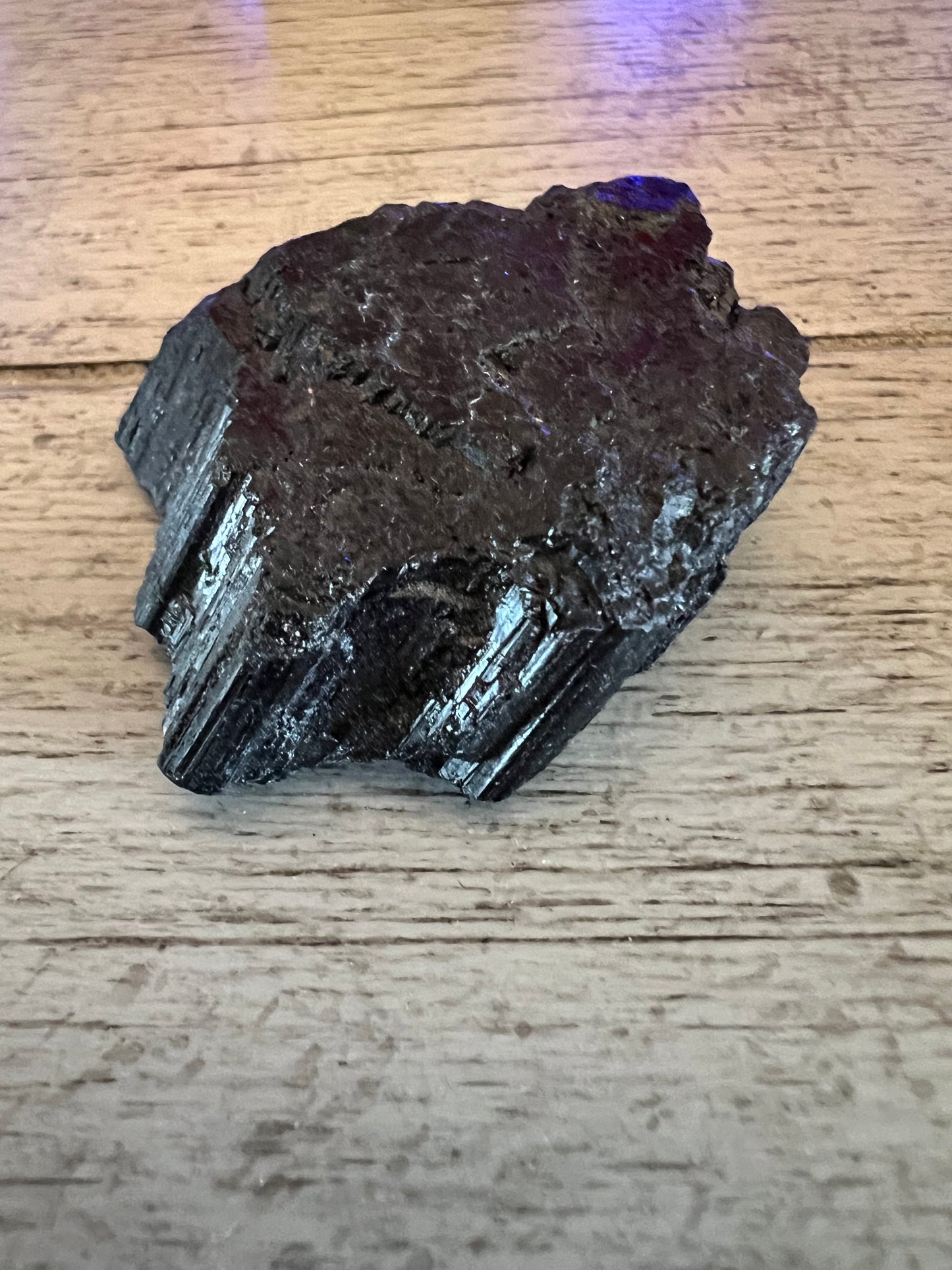 Black tourmaline stone on a wood surface.