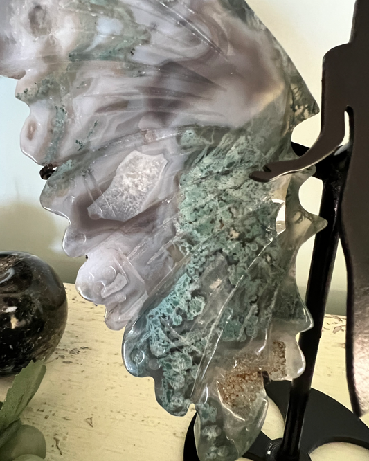 Close-up of a gray and green agate butterfly mounted on a black metal stand.