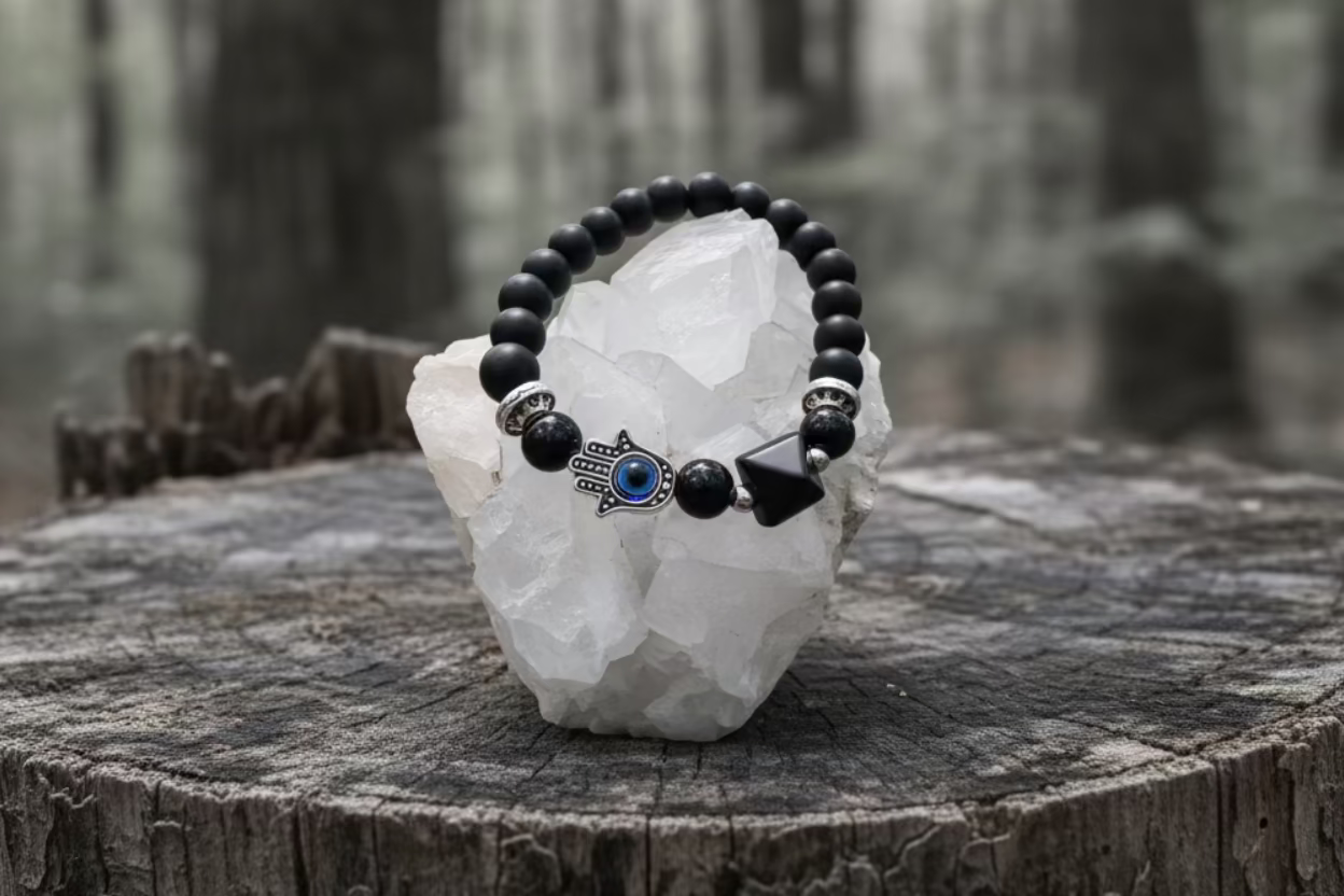 Black Obsidian Bracelet with Black Obsidian pyramid charm and Hamsa Charm on a tree stump in the forest