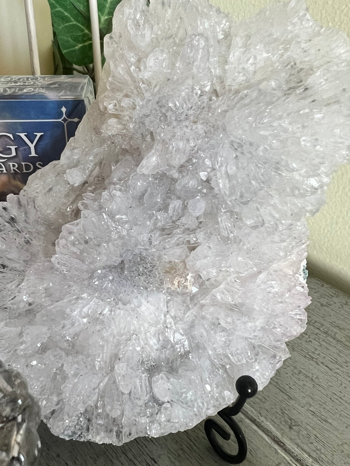 A large, shimmering white crystal formation is displayed on a black metal stand.