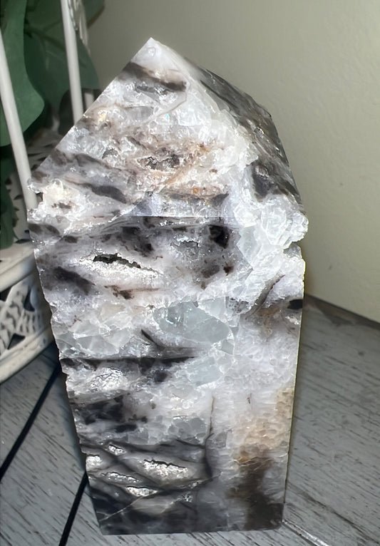A tall, cut and polished black and white agate geode, standing on a gray wooden surface.