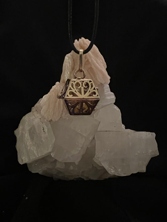 A necklace with a gold pendant on a white crystal.