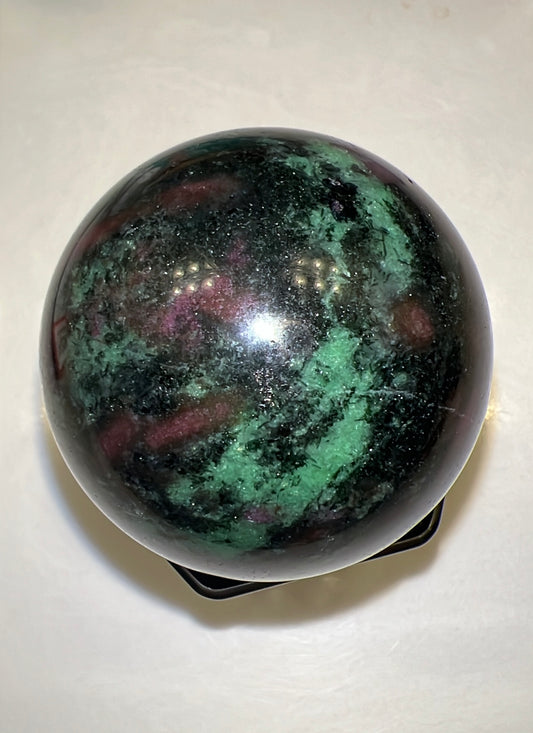 Polished ruby in zoisite sphere with black stand.