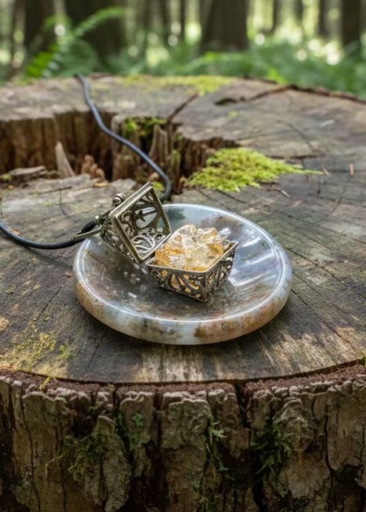 Open gold locket with citrine crystals on round agate pendant with black cord.