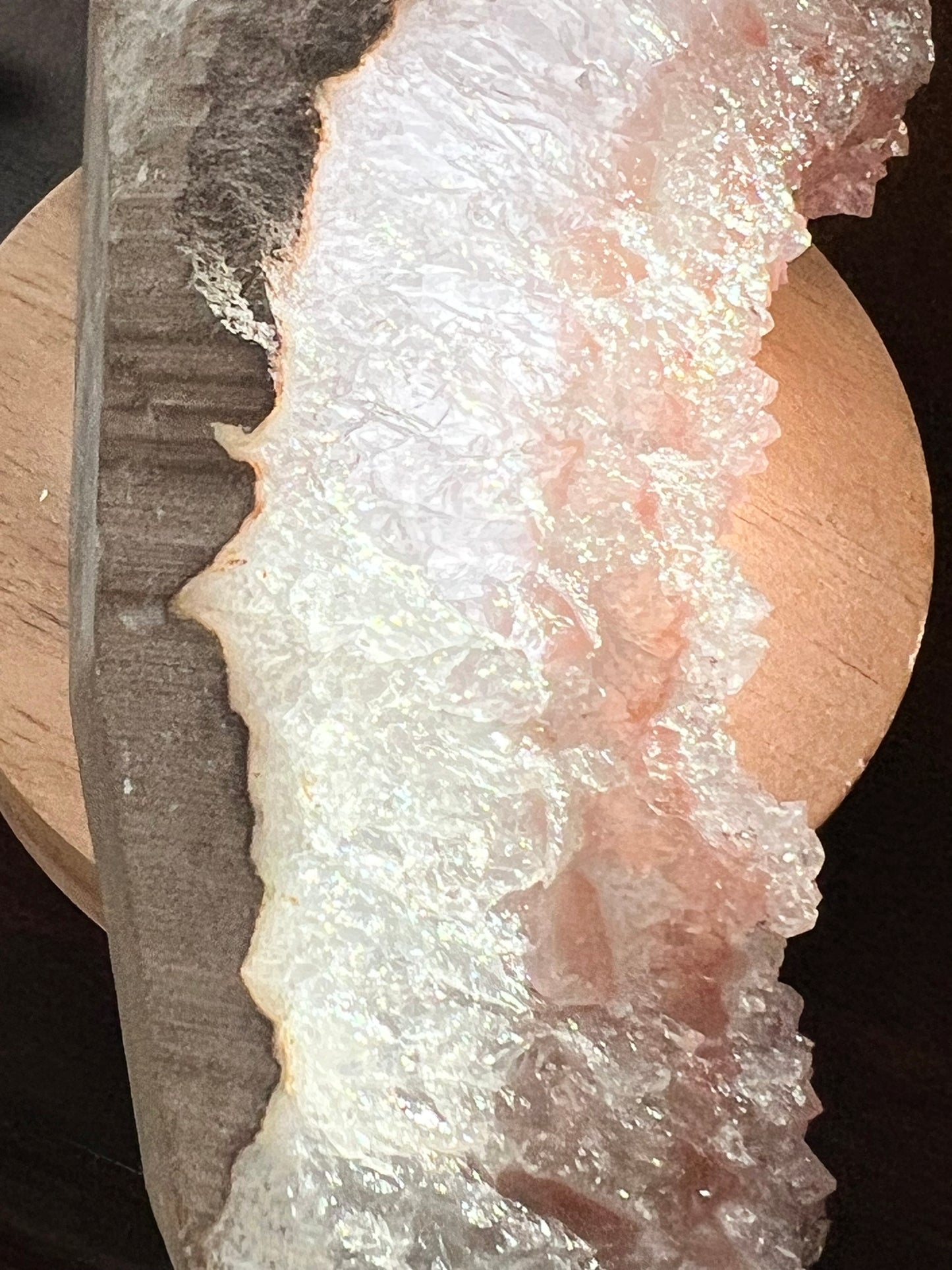 Close-up of pink and white crystalline mineral mounted on wood base.
