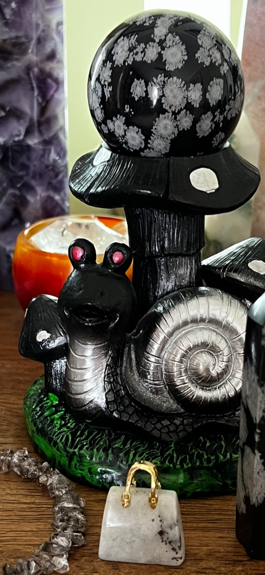 Snail figurine with mushroom cap and snowflake obsidian sphere.