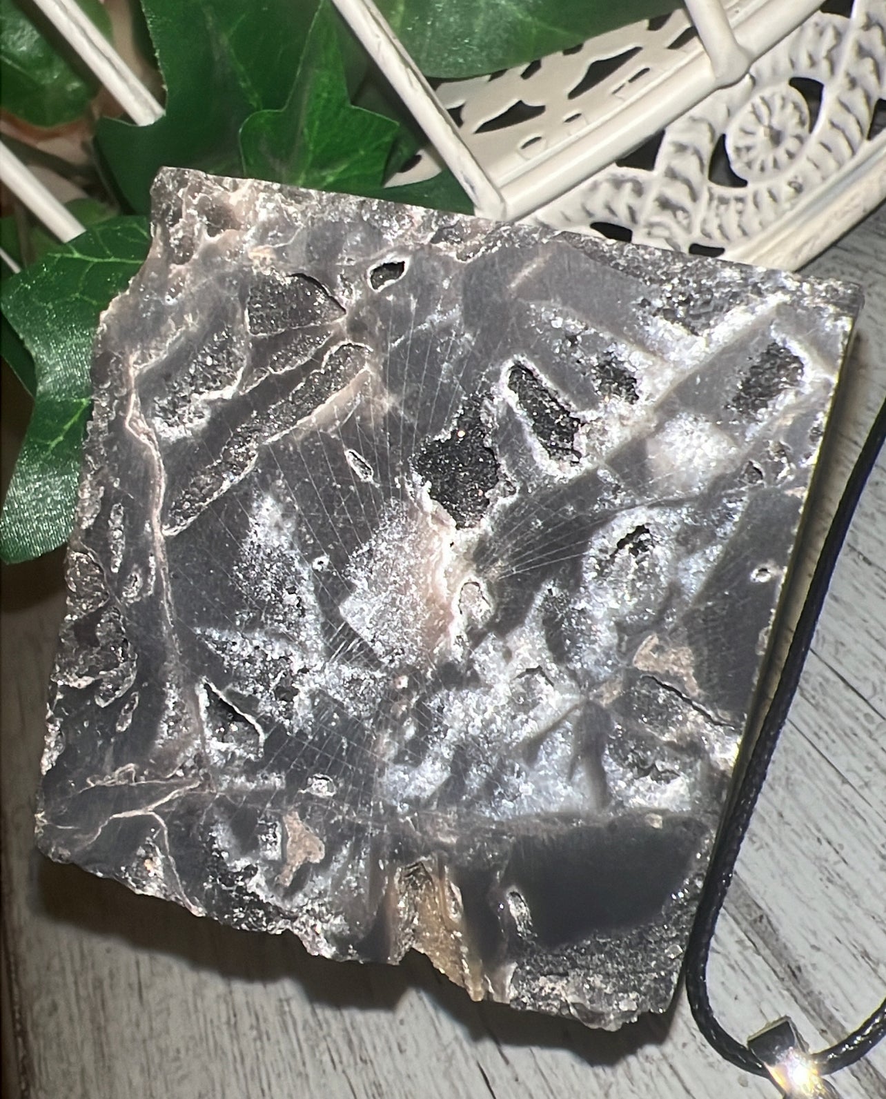 Polished slab of lace agate with black and white bands, on a rustic wooden surface.