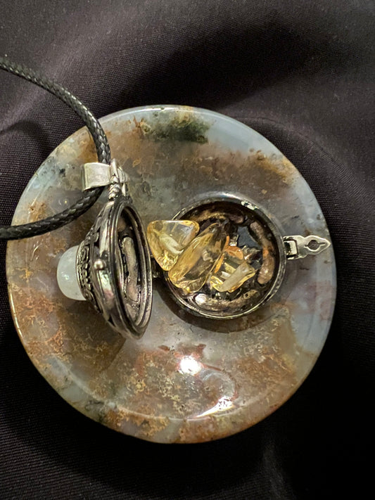 Open locket with yellow stones on a moss agate pendant with a black cord.