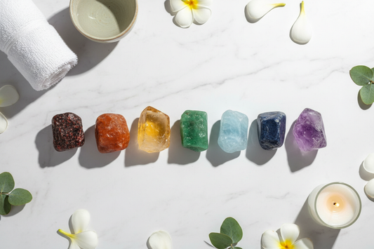 even chakra crystals arranged in a line from red to violet on a white surface representing the seven energy centers