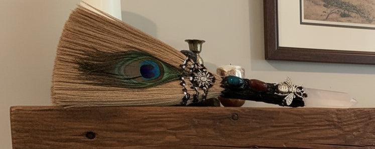 Hand crafted besom / altar broom clear quartz finial natural bristles silver bee charm and rare peacock feather  on a fireplace mantle