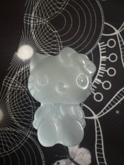 A pale blue Hello Kitty figurine on a black surface with white geometric designs.