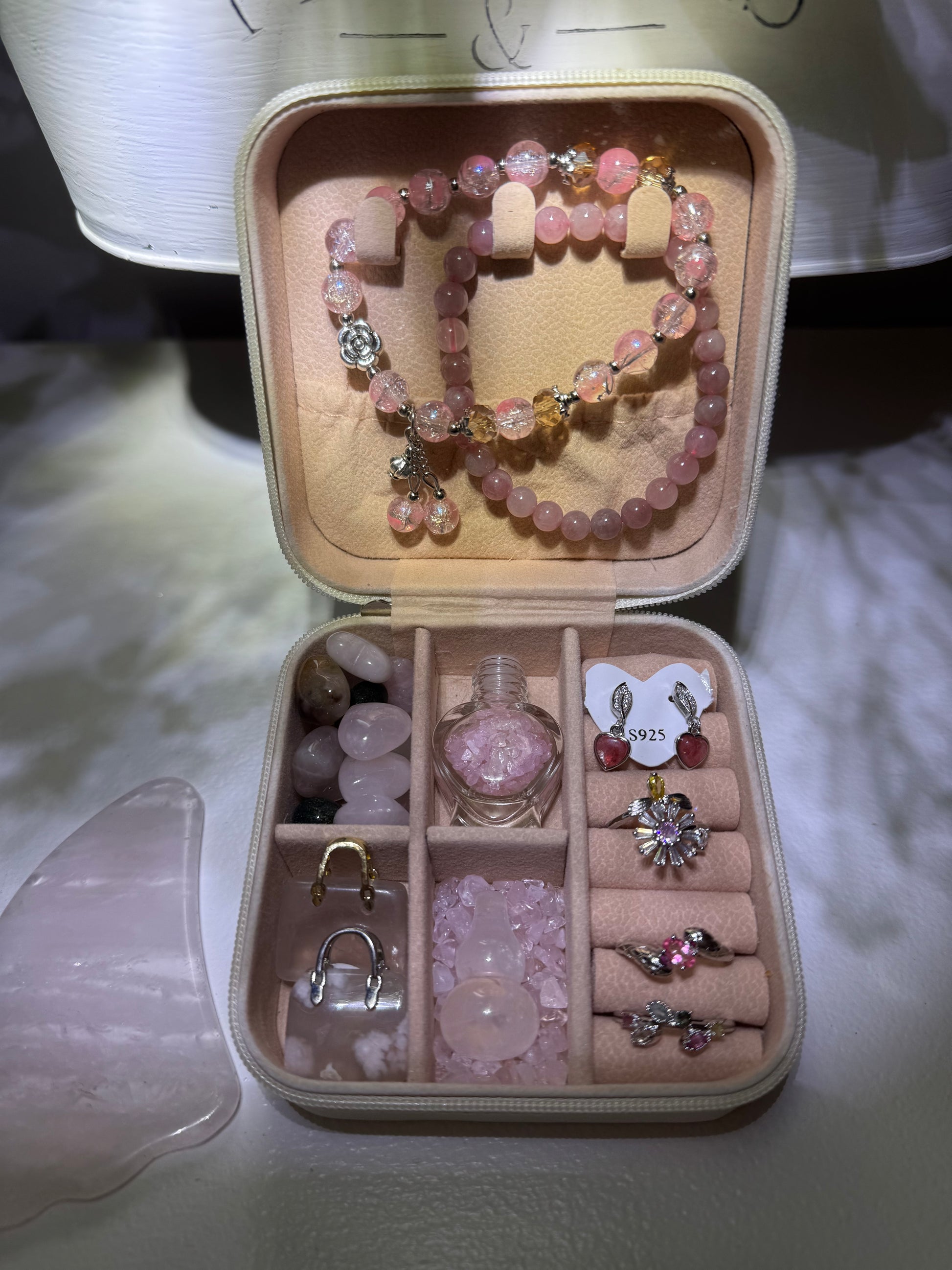 Open jewelry case with pink quartz jewelry and crystals. 
