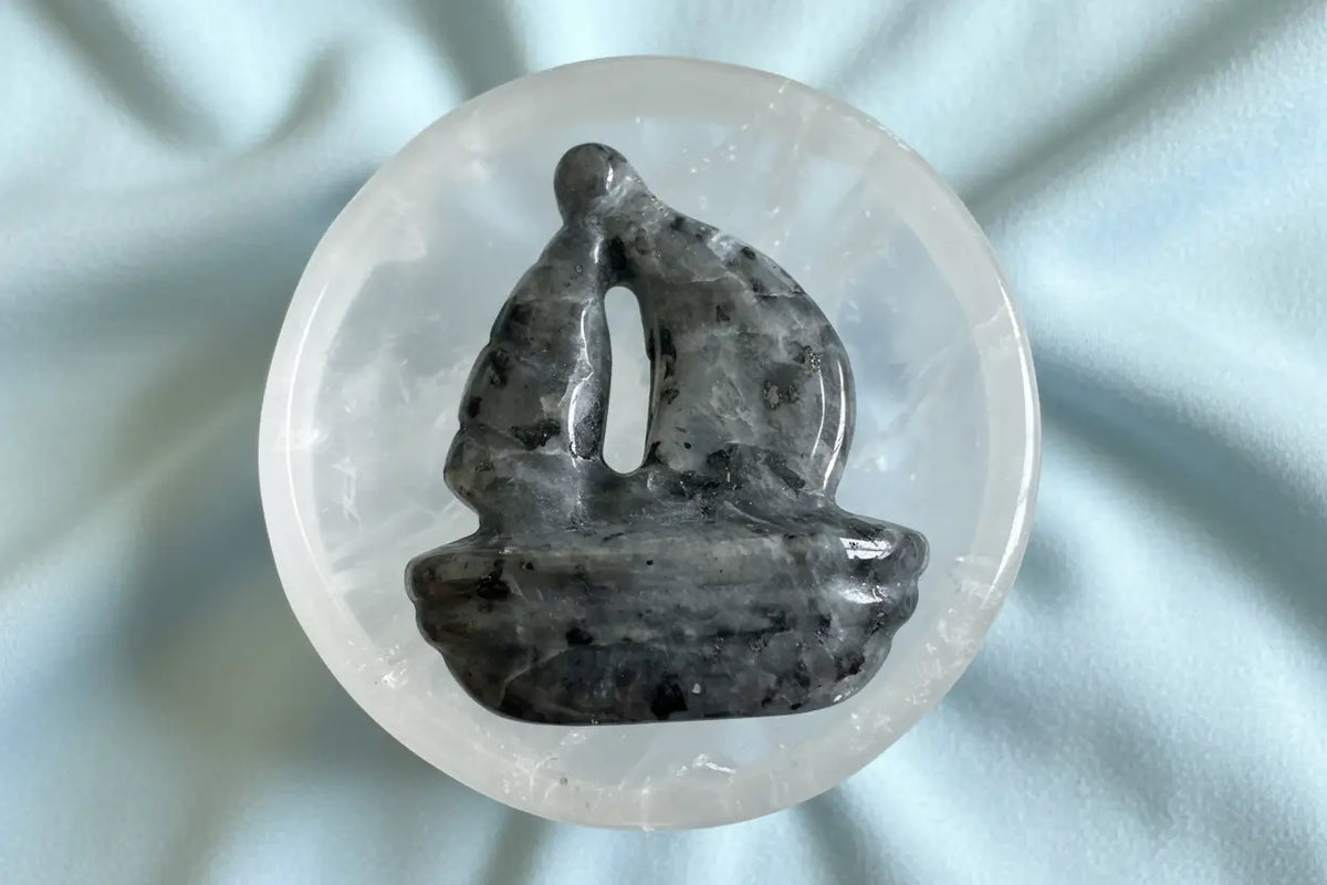 Crystal sailboat carving displayed in Clear Quartz bowl
