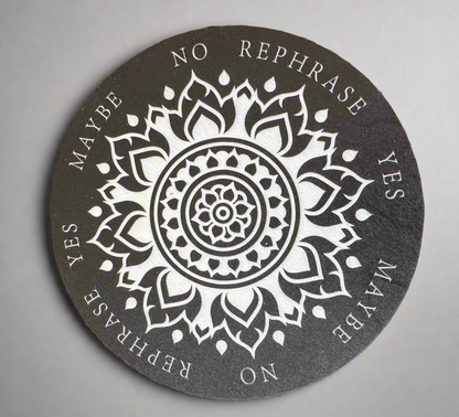 A black and white round divination board with a mandala pattern and the words "Yes," "No," "Maybe," and "Rephrase" printed around the edge.
