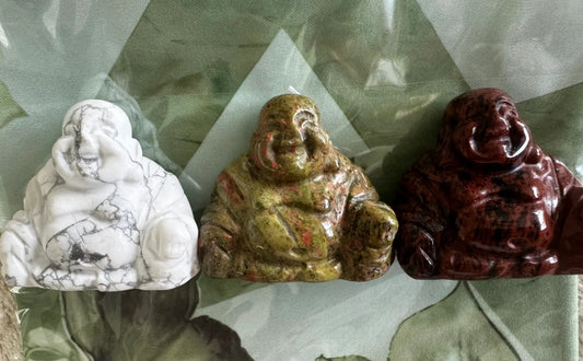 Three small Buddha statues made of different stones. 
