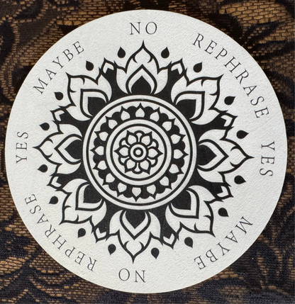 Circular divination board with floral mandala design. "Yes," "No," "Maybe," and "Rephrase" options. Lace background.
