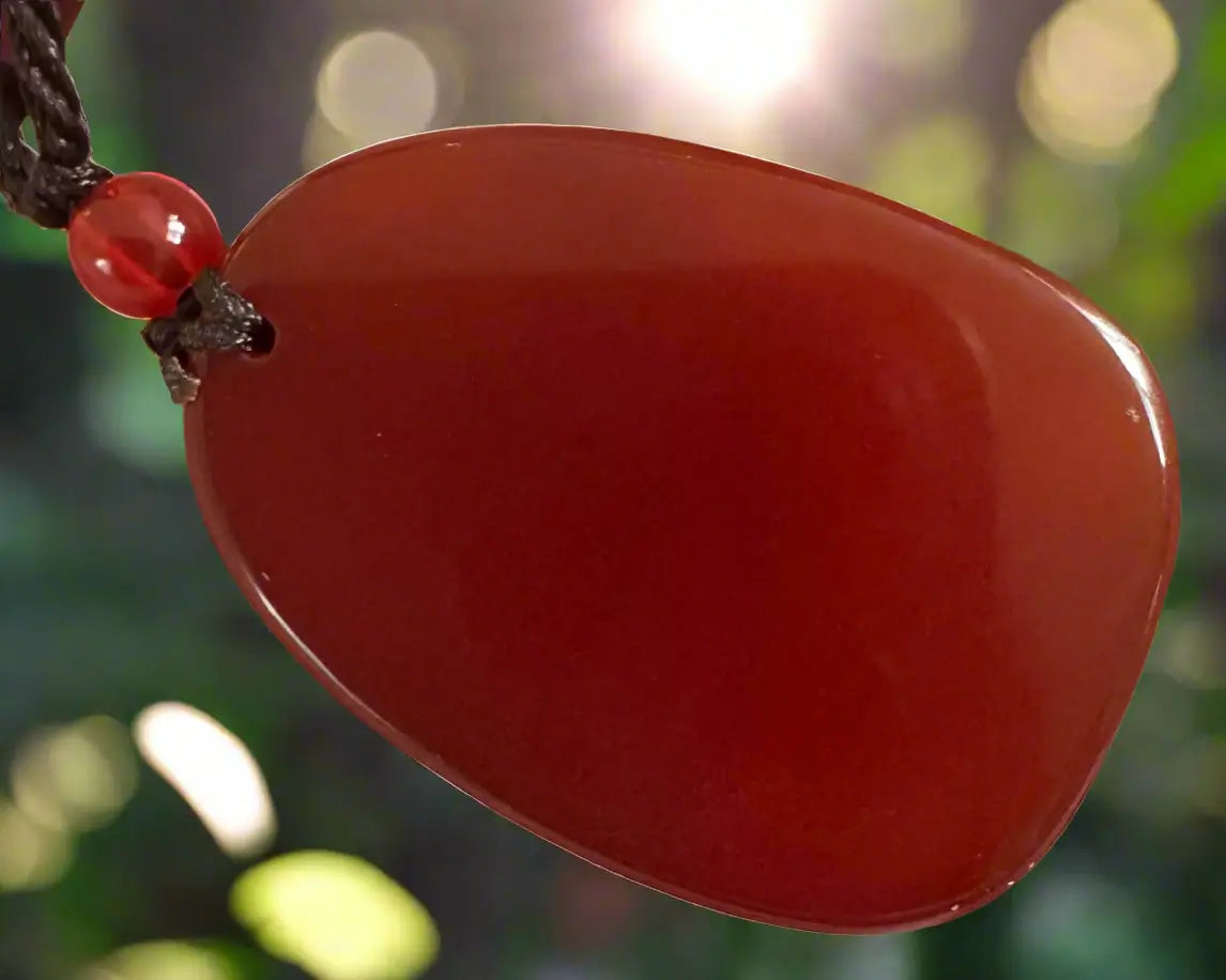 Red pendant necklace with a dark brown cord.