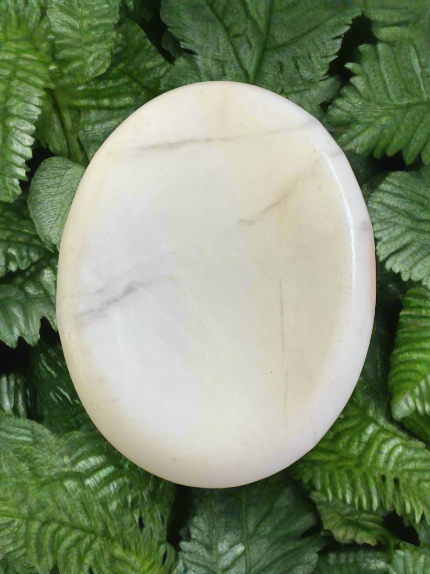 Round, white, veined stone on green ferns.
