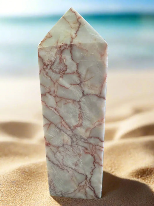 Rough cut red vein jasper tower on sandy beach
