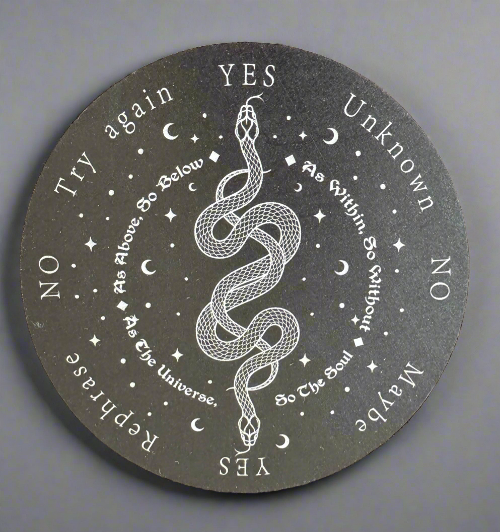 Close-up of a dark, round divination board with white lettering, featuring a snake coiled in the center.