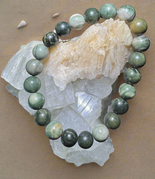 A green jade bead bracelet displayed atop white and beige-colored minerals.