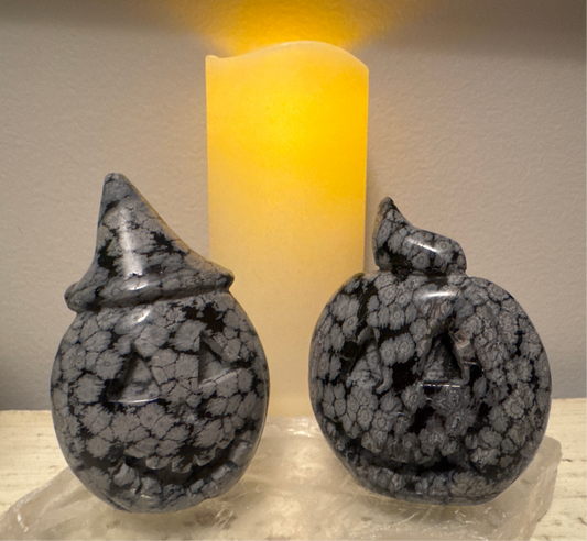 Two carved stone jack-o'-lanterns and a yellow candle.