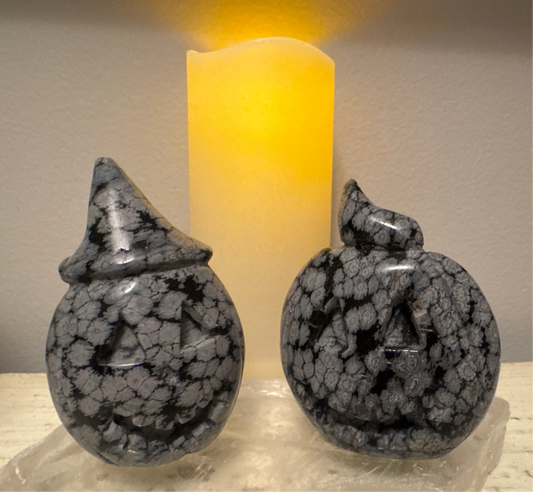 Two carved stone jack-o'-lanterns and a yellow candle.