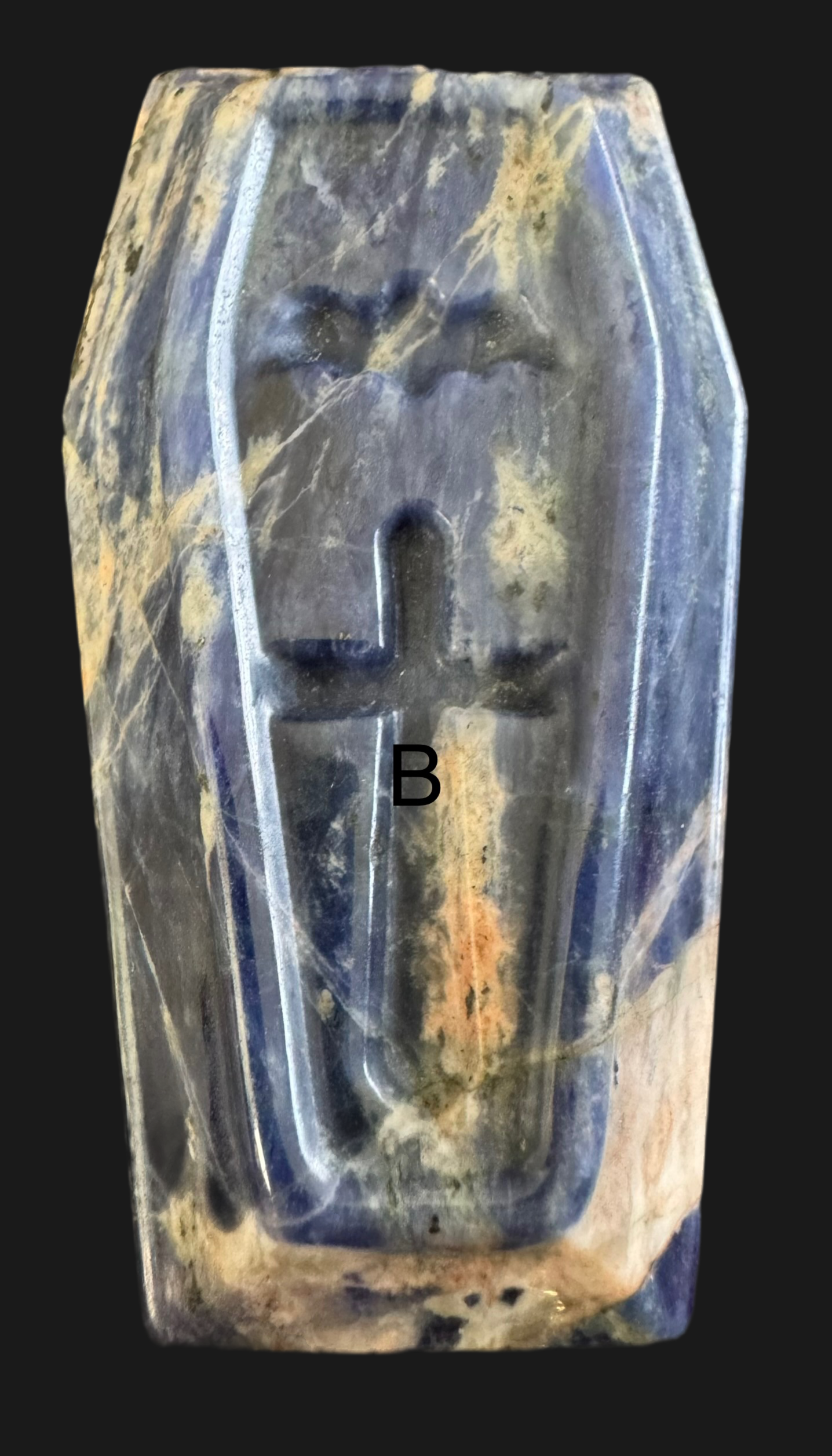 Blue stone object carved in the shape of a coffin with cross design.