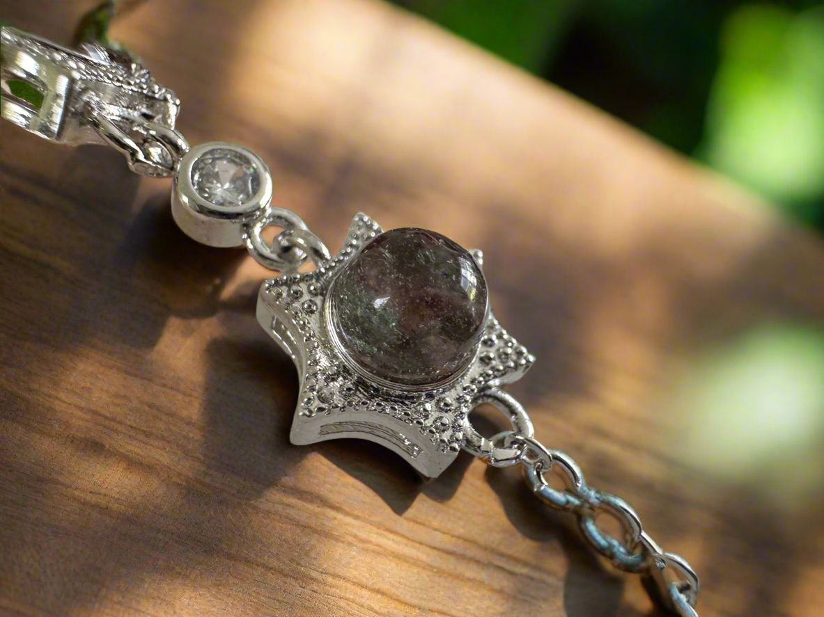 Close-up of a silver star bracelet featuring a dark, speckled gem, resting on a wooden surface.