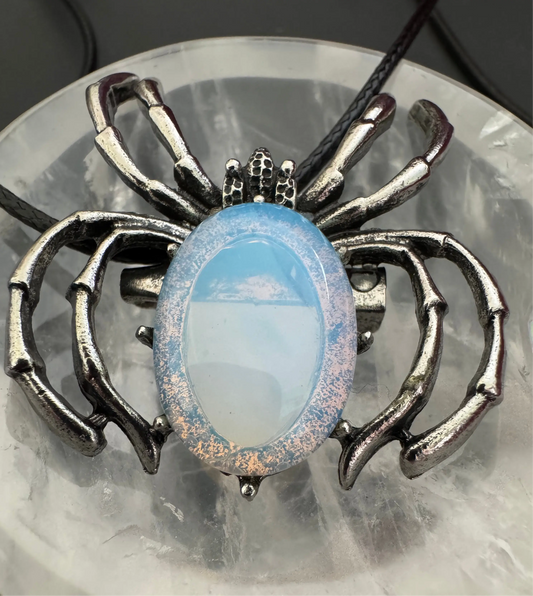 Silver spider pendant with oval blue and white opal on a leather cord.
