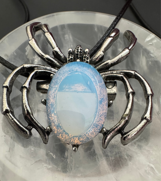 Silver spider pendant with oval blue and white opal on a leather cord.
