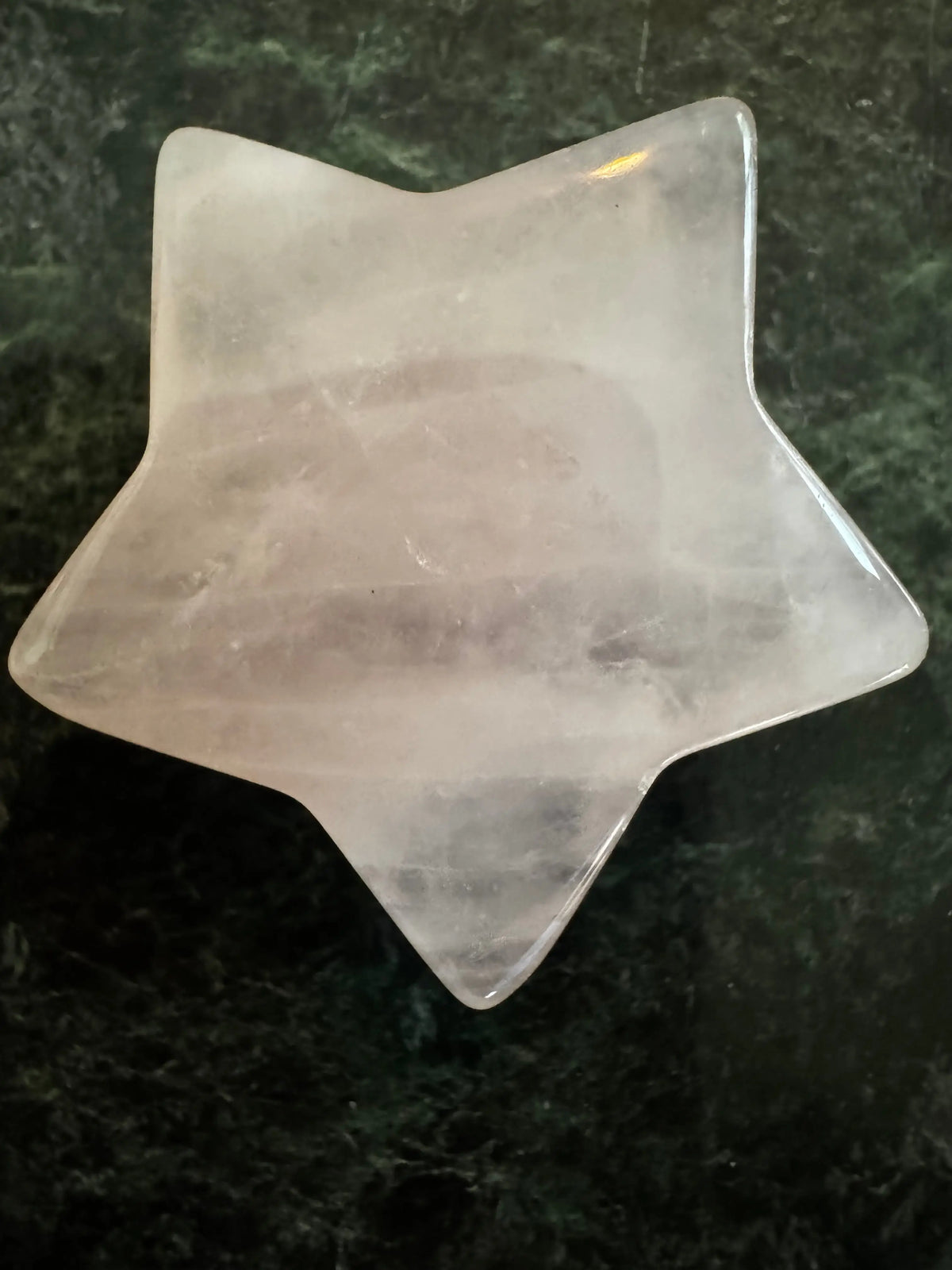 Rose quartz carved star on a green background