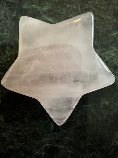 Rose quartz carved star on a green background