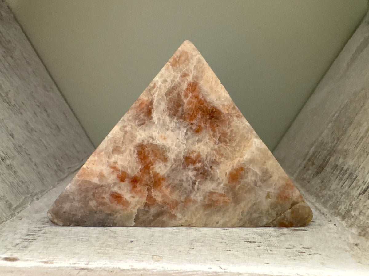 Sunstone pyramid on weathered wood.