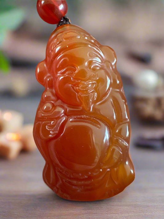 Close-up of a smiling orange Buddha pendant.
