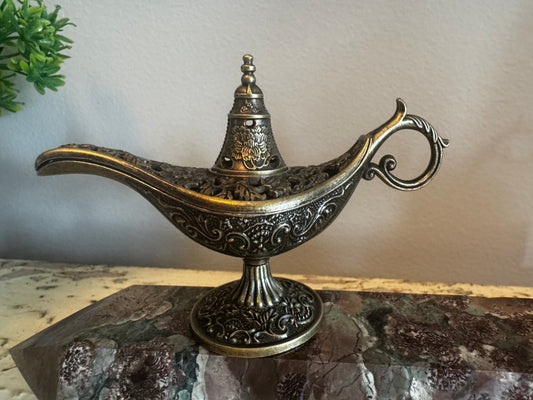 Ornate metal genie lamp on a marble surface. 
