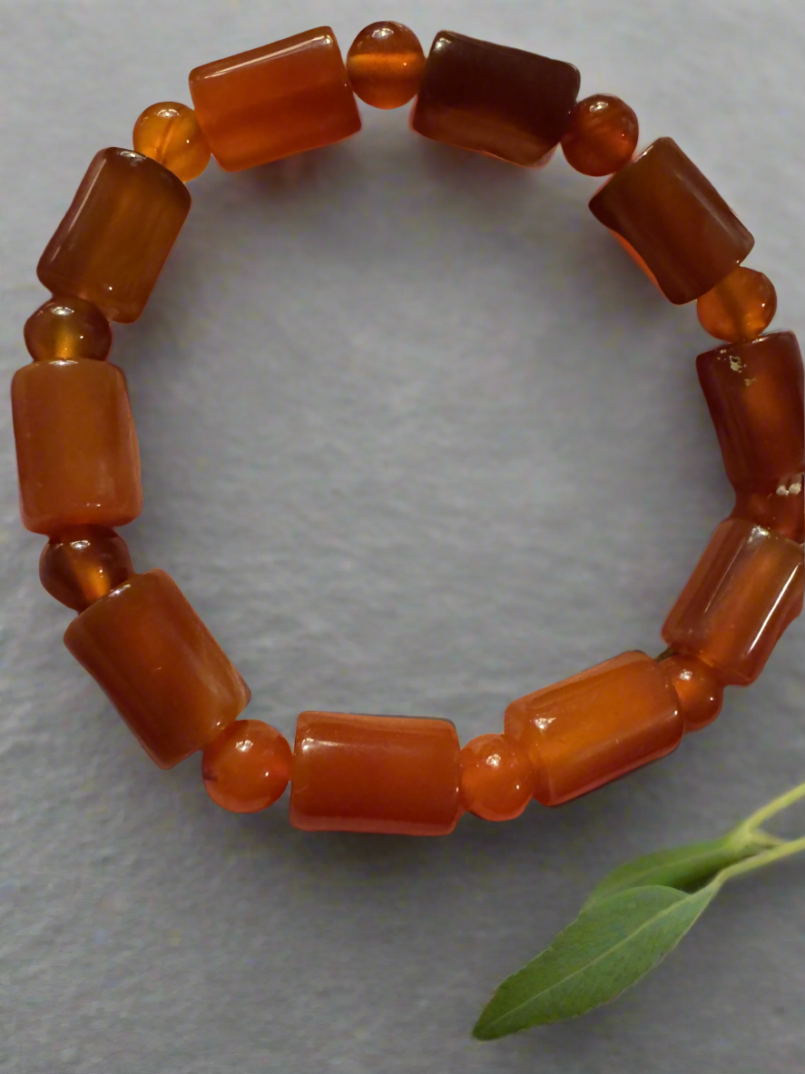 Orange beaded bracelet with cylindrical and spherical beads.
