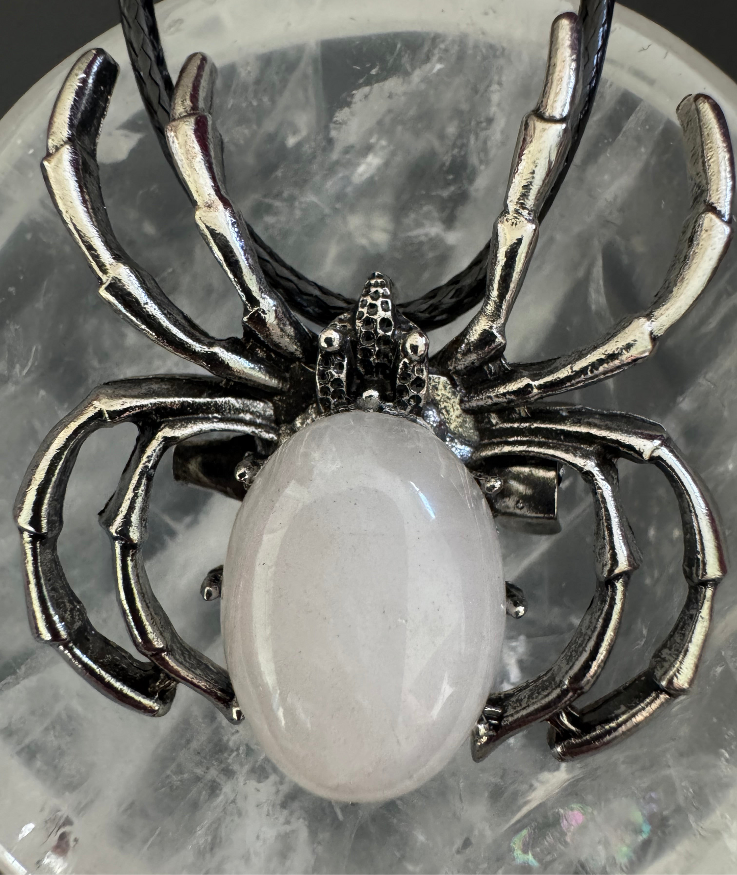 Spider necklace with a pink stone on a rock.