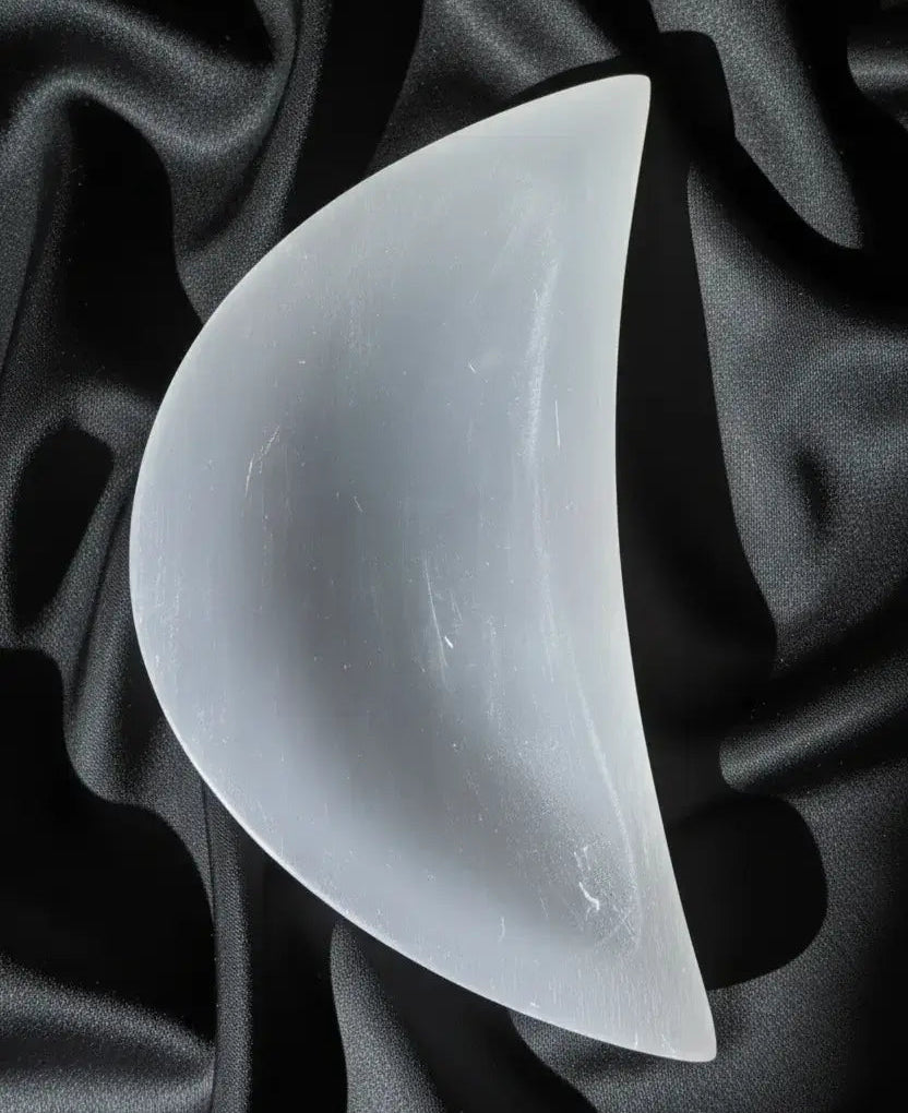 White selenite moon with embedded butterfly on patterned cloth.