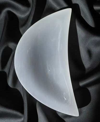 White selenite moon with embedded butterfly on patterned cloth.