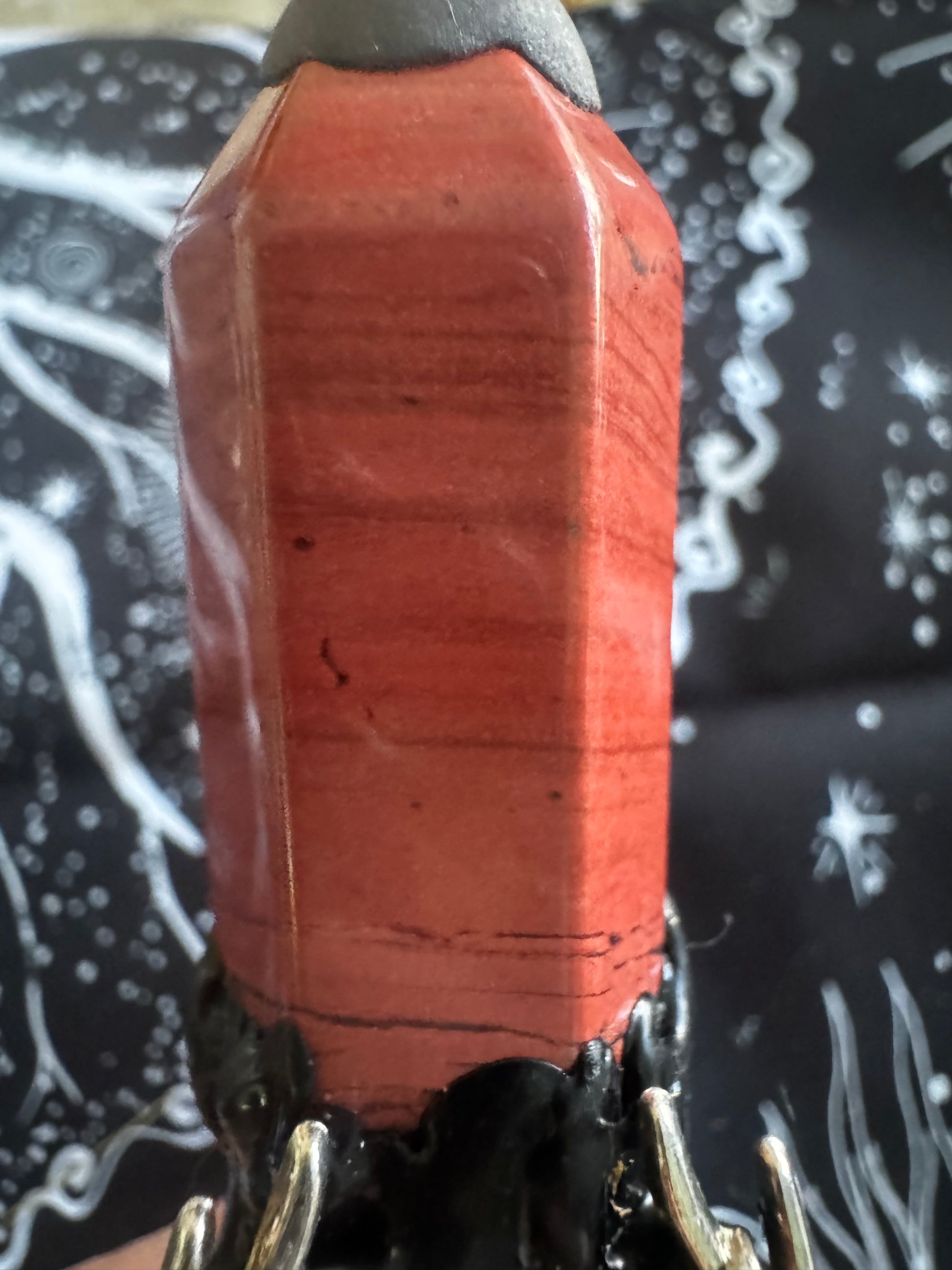 Red and brown crystal point with black and silver base.