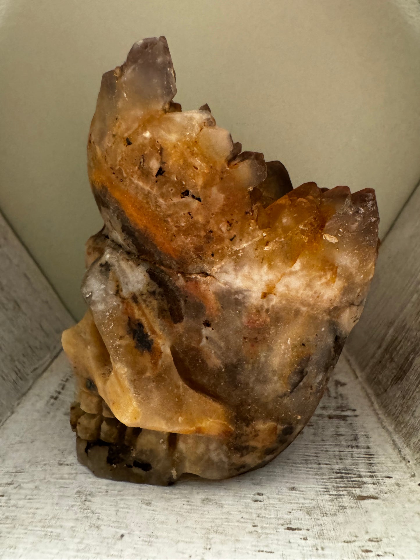 Carved citrine skull sculpture on white wooden shelf.
