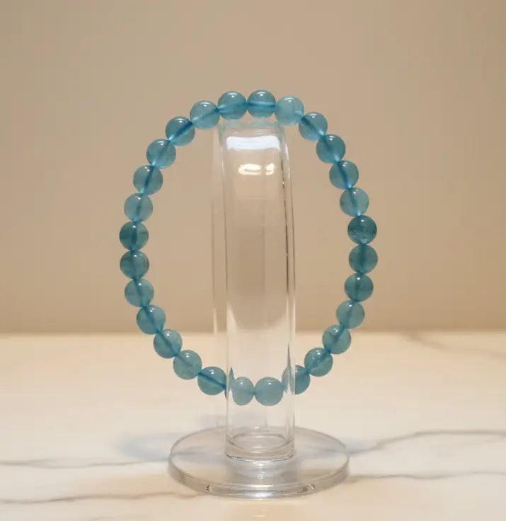 photo of a beautiful 7.5 mm beaded aquamarine bracelet on a glass stand marble table and light background