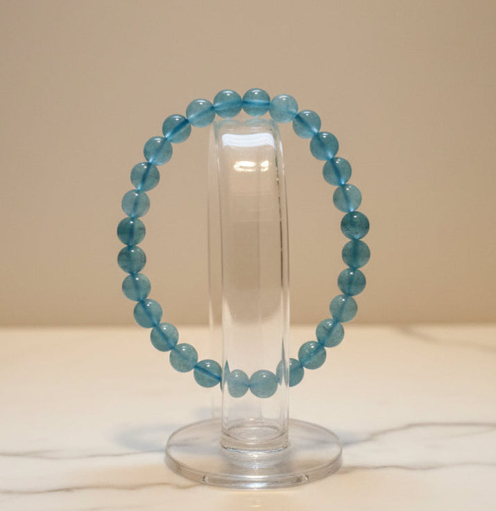 photo of a beautiful 7.5 mm beaded aquamarine bracelet on a glass stand marble table and light background