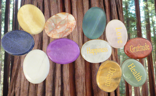 Assorted palm stones with positive affirmations on wood background.