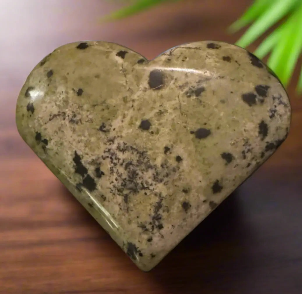 Close-up of a green heart-shaped stone with black speckles.
