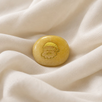 yellow aventurine carved worry stone with gold tone etching on one side of a Santa Face